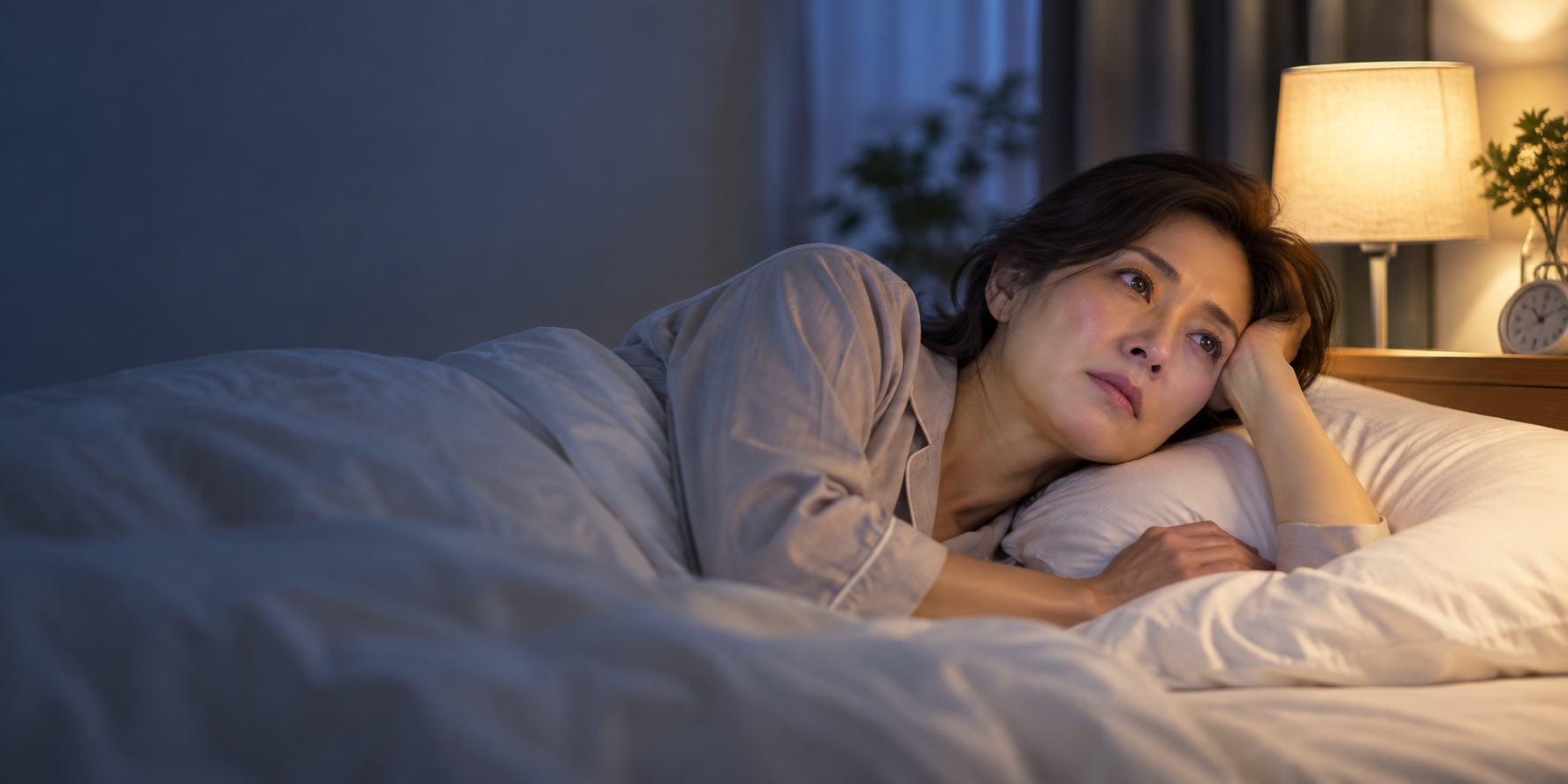 夜、なかなか眠れずベッドで過ごす女性